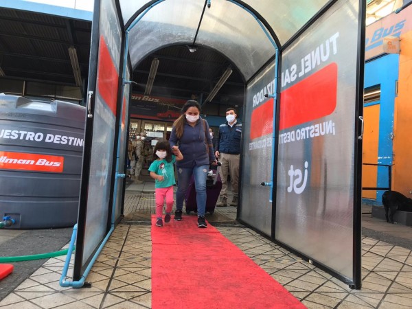 Pasajeros atravesando el primer túnel sanitizador de buses interurbanos